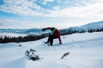 Naklejka na ściany i meble snowboarder falling while riding on slope in mountains