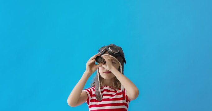 Happy child looking at spyglass against blue background