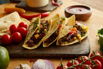 Fresh tacos with minced meat and vegetables on wooden table