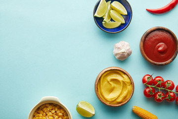 Top view of lime, mustard with tomato sauce and vegetables on blue background