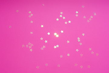 Flatlay with star-shaped glimmering sequins on pink background. Festive party concept