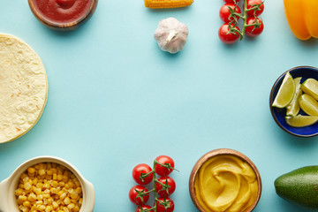 Top view of tortillas with taco ingredients on blue background