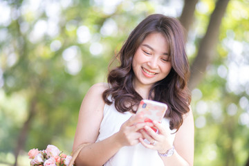 Beautiful smiling women use smartphone while leisure in city freen park