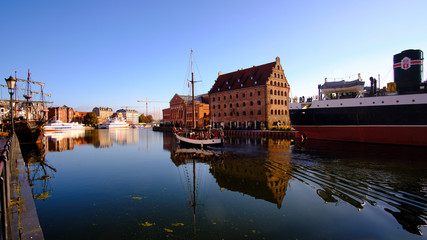 Traditional sailing boat, with unrecognizable people passing by the baltic Philharmonie on Motława river in Gdansk, Poland