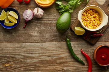 Top view of fresh vegetables, fruits and sauces on wooden surface with copy space