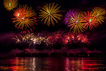 Fototapeta na wymiar Bright festive fireworks reflected in the river