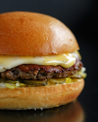Appetizing juicy burger on a dark background. Close-up