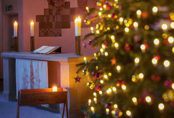 warmer, softer Kerzenschein und Lichterglanz im Altarraum einer Kirche mit Weihnachtsbaum