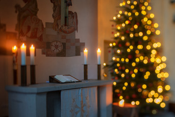warmer, softer Kerzenschein und Lichterglanz im Altarraum einer Kirche mit Weihnachtsbaum