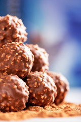 Pile of chocolate candies with nuts close-up, selective focus. Chocolate truffles lie on cocoa powder.