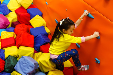 Girl climbing on a wall in attraction playground