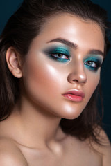 Fototapeta premium Portrait of a beautiful young model with bright blue trendy smoky eyes, blue eyes, perfect skin and natural lips.