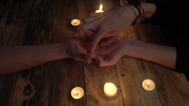 Palmistry concept. Fortune teller reading the lines of good fortune on her hand, candles and smoke are burning in the background.