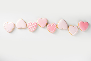 Homemade pick sugar glazed Valentine day cookies. Valentine heart shaped bakings. White stone background copy space top view