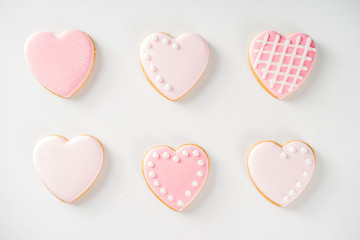 Homemade pick sugar glazed Valentine day cookies. Valentine heart shaped bakings. White stone background copy space top view