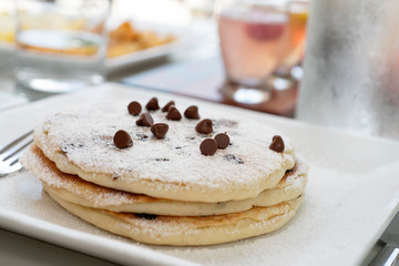 pancakes with chocolate chips and drinks in the background 