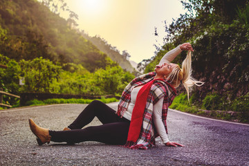 Blonde girl, living crazy, sitting in the middle of the road with her tongue out.