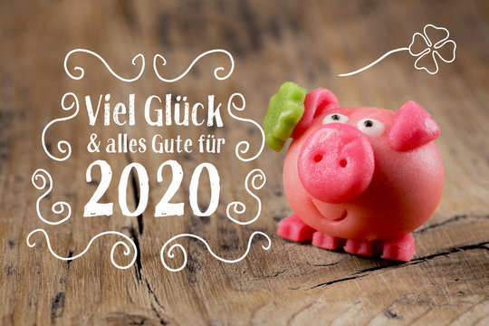New year card 2020, german language  -  Good luck and best wishes for 2020 -  Marzipan pig on rustic wooden background  -  Good luck symbol