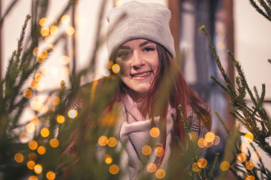 Portrait of a beautiful fashionable girl in a hipster hat on a winter street with festive lights bokeh. Lifestyle.