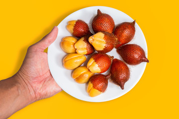 Salak fruit, Salacca zalacca in dish on the table and orange background.