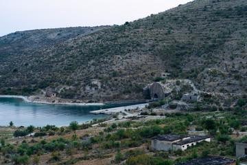 Fototapeta premium Beautiful landscape with high mountains with illuminated peaks, stones in mountain lake, reflection, yellow sunlight in sunrise. Seaview and beautiful sunset. Photo by drone. Horizontal photo.