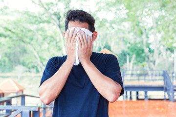 Man wiping off the sweat on face  because hot weather  in the parks
