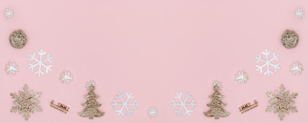 New Year and Christmas composition, banner. Frame from golden christmas ball, snowflake, chrismas tree, gift bows, sleigh on pastel pink paper background. Top view, flat lay, copy space.