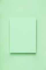 Minimal frame geometric composition mock up. Blank sheet of green paper on green background. Template design invitation card. Top view, flat lay, copy space. Horizontal orientation.