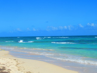 Fototapeta na wymiar Une plage de sable blanc devant la mer turquoise avec des vagues