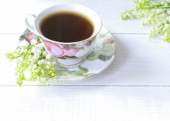 a cup of black coffee and a bouquet of lilies of the valley close-up.