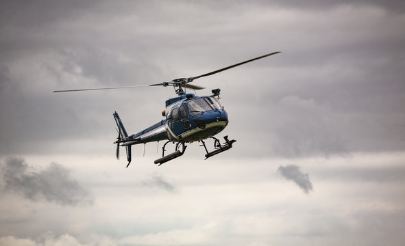 Blue helicopter in flight over gray sky