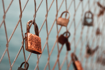 Colored rusted love padlocks with initials on a fence in split croatia , dramatic cold day. Concepts of love drama