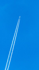 Obraz premium Two engined airplane during flight in high altitude with condensation trails