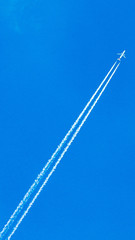 Two engined airplane during flight in high altitude with condensation trails