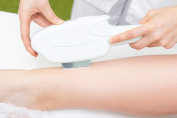 laser hair removal. the girl removes hair with a laser on her legs in a spa salon. the master holds a laser and removes hair.
