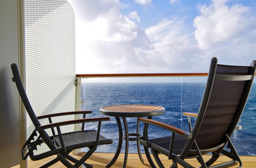 Deck chairs or sun loungers with table on balcony or terrace or patio of luxury cabin stateroom...