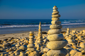 Fototapeta na wymiar Pyramid of stones on the sea and sky background