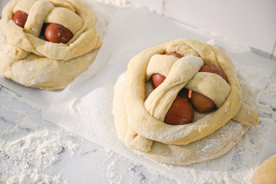Top view of uncooked Easter cakes with three eggs, also called folar or Folares, being prepared to cook.