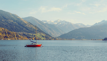  Panoramic view of beautiful mountain landscape in Alps with Zeller Lake in Zell am See, Salzburger Land, Austria. Red yaht at calm water Wonderful Lake. under bright sunlight