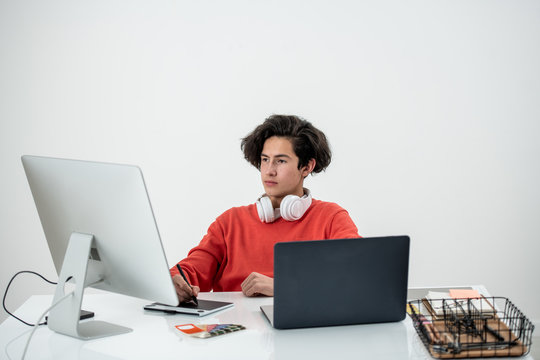 Young serious male freelancer retouching images in front of computer monitor