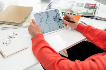 Hands of creative fashion designer with stylus pointing at one of new models