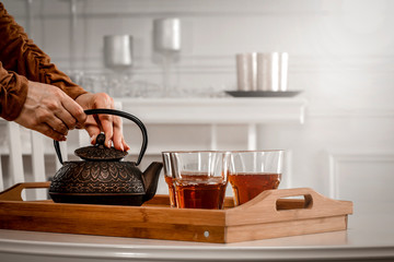 Woman hands with kettle and hot tea 