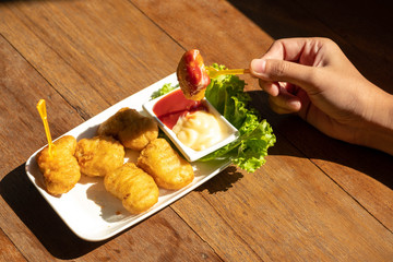 Eating chicken nuggets with two dipping sauce.