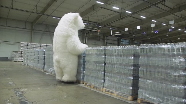 Happy white bear doll giant running through the beer warehouse and enjoys the many boxes of beer.