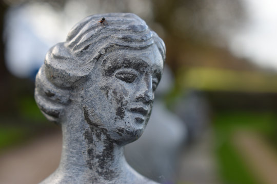 A sculpture of a woman in a european garden which can be seen in the background. Great for use as a concept to describe european culture and history