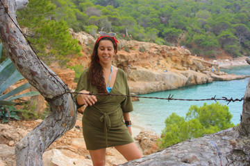 Naklejka premium caucasian girl on the cliff of cala saladeta enjoys summer vacation in the wild nature of the balearic islands