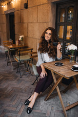 Girl sitting on a summer terrace of a cafe with a cup of cappuccino