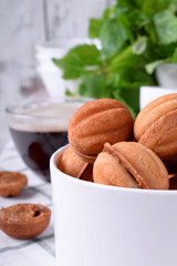 Walnut shaped cookies with condensed milk in a round box against white background