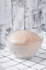 Yeast dough in a glass bowl ready to be formed into bakery products against white background