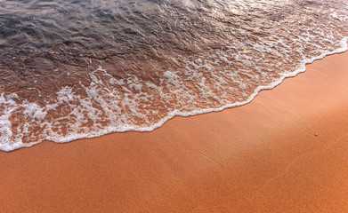 Awesome nature background. Soft beautiful ocean wave on sandy beach with during sunset. Backdrop